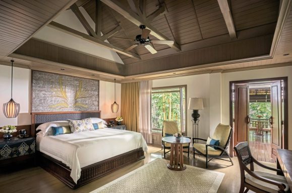 Luxuriöses Schlafzimmer mit Holzdecke, großem Bett und gemütlicher Sitzecke.