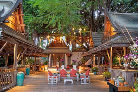 Tropischer Innenhof mit Holzstrukturen, gemütlichen Sitzgelegenheiten und Pflanzen.