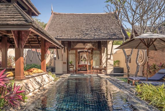 Tropischer Innenhof mit Pool, umgeben von einem traditionellen thailändischen Gebäude.