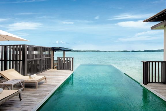 Luxuriöser Infinity-Pool am Meer mit Liegen und Sonnenschutz.