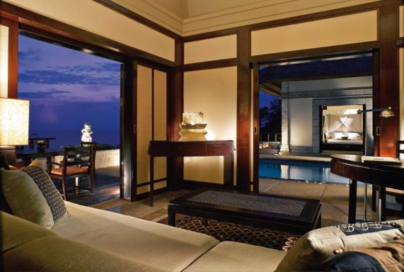 Modern Wohnzimmer mit Panoramablick auf einen Pool bei Sonnenuntergang.