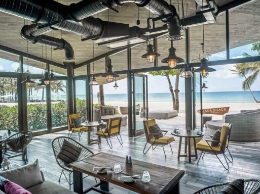 Moderne Strandbar mit Holzdekor, großen Fenstern und Blick auf den Ozean.