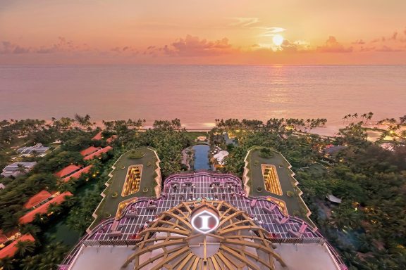 Blick auf die Küste bei Sonnenuntergang mit Palmen und Resorts im Vordergrund.