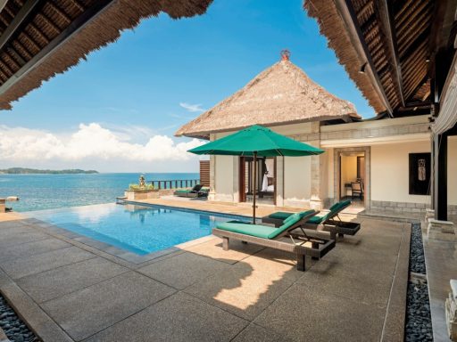 Luxuriöser Poolbereich mit Liegen und Blick auf das Meer, umgeben von tropischer Vegetation.