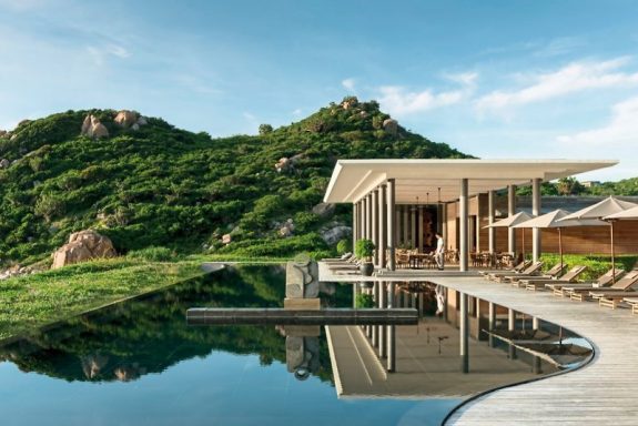 Moderne Villa am Wasser mit Blick auf grünes Hügelpanorama.