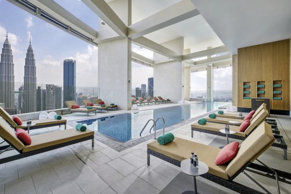 Elegante Terrasse mit Liegen, Blick auf die skyline von Kuala Lumpur und einen Infinity-Pool.