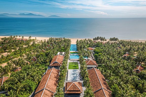 Luftaufnahme eines tropischen Resorts mit Blick auf Strand und Poolanlage.
