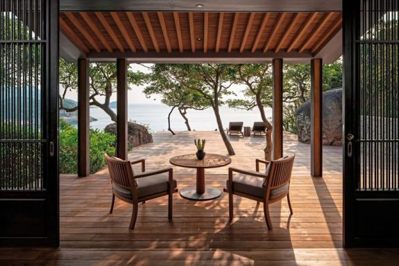 Gemütliche Terrasse mit zwei Stühlen und Blick auf den Strand und das Wasser.