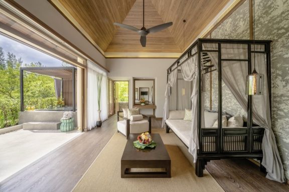 Helles, modernes Zimmer mit einem Bett, Sofa und großer Fensterfront zur Natur.