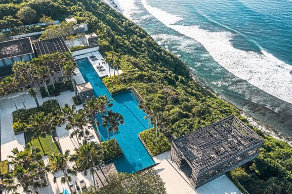 Luxuriöse Anlage mit Infinity-Pool und Blick auf das Meer, umgeben von Palmen.