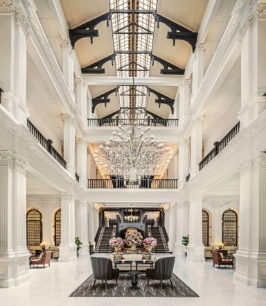 Elegante, helle Lobby mit hohen Decken, Kronleuchtern und stilvoller Einrichtung.