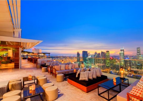 Dachterrasse mit Sitzgelegenheiten und Blick auf die Stadt bei Sonnenuntergang.