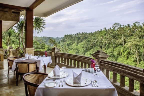 Elegant Tischgedeck mit Blick auf eine grüne, bewaldete Landschaft.