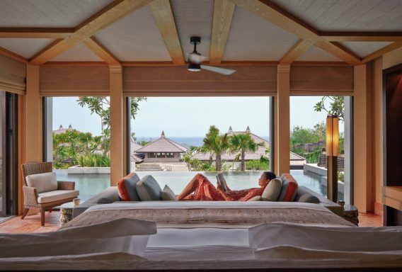 Luxuriöses Schlafzimmer mit Blick auf einen Pool und tropische Landschaft.