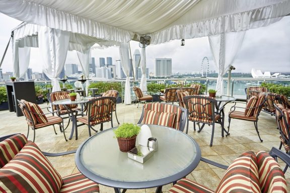 Elegante Terrasse mit gestreiften Stühlen und Blick auf die Stadt.