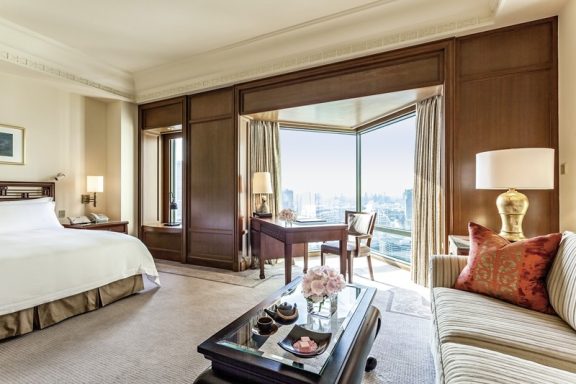 Ein elegantes Hotelzimmer mit Stadtblick, Bett, Schreibtisch und gemütlichem Sofa.