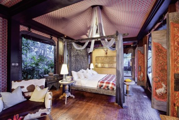 Schönes Schlafzimmer mit Holzmöbeln, gemütlicher Bettwäsche und großen Fenstern.