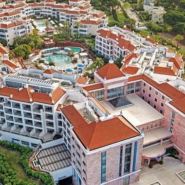 Steinernes Landhaus, das Pula Golf Resort, mit Garten und Brunnen, umgeben von blühenden Pflanzen.