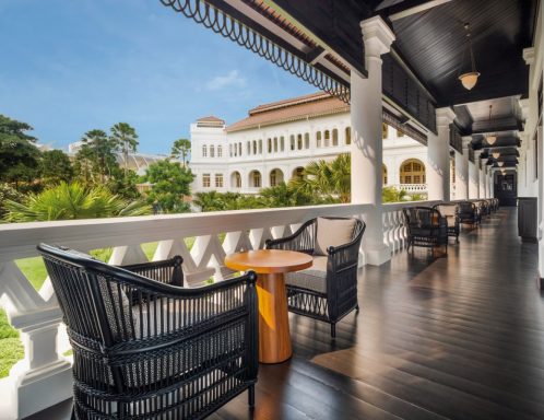 Elegante Terrasse mit Stühlen und Tisch, umgeben von üppiger grüner Landschaft.
